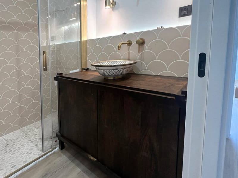 Baño con ducha de obra, mampara de cristal y mueble de madera en Ferrol