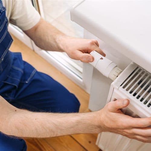 Técnico ajustando la válvula termostática de un radiador en una vivienda de Ferrol