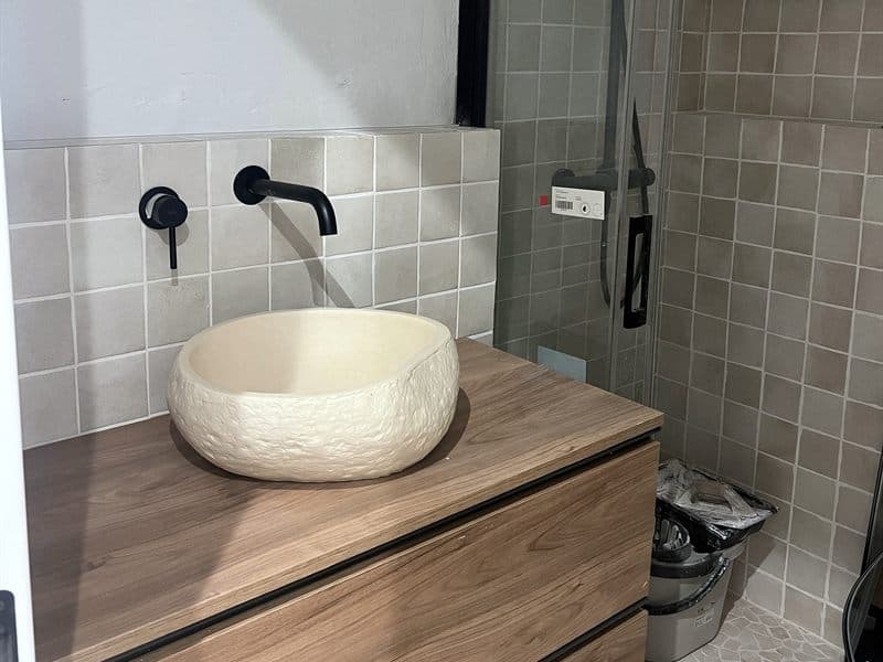 Lavabo de piedra y grifería negra instalados junto a la ducha en Ferrol