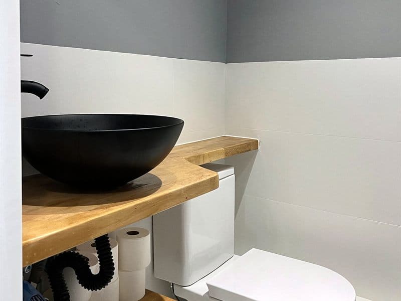 Inodoro y lavabo sobre encimera de madera en un baño reformado en Ferrol
