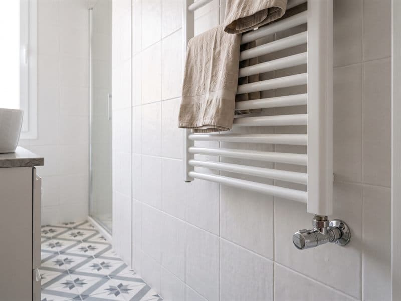 Radiador toallero blanco instalado en un baño reformado en Ferrol