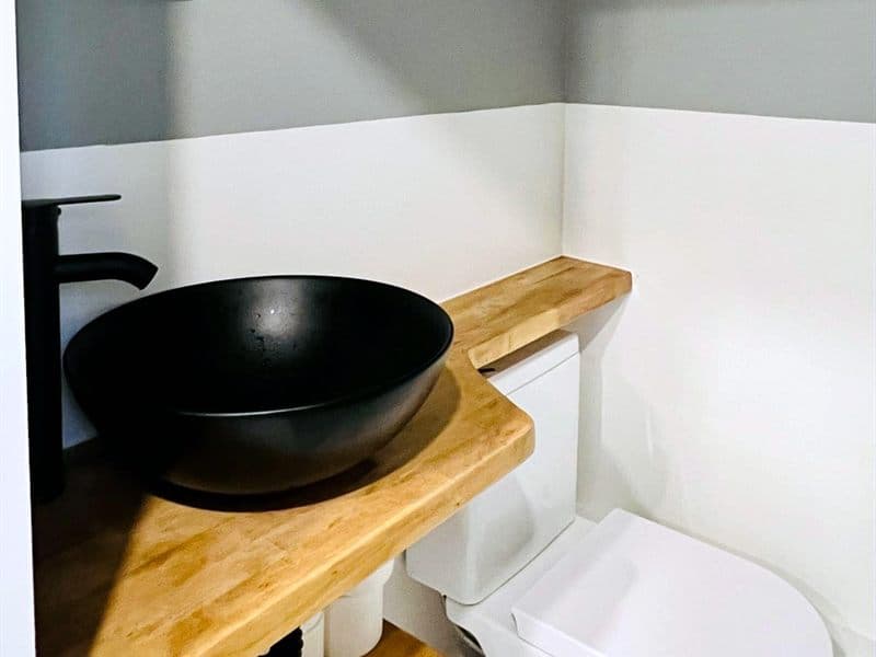 Lavabo negro sobre encimera de madera en un baño reformado en Ferrol