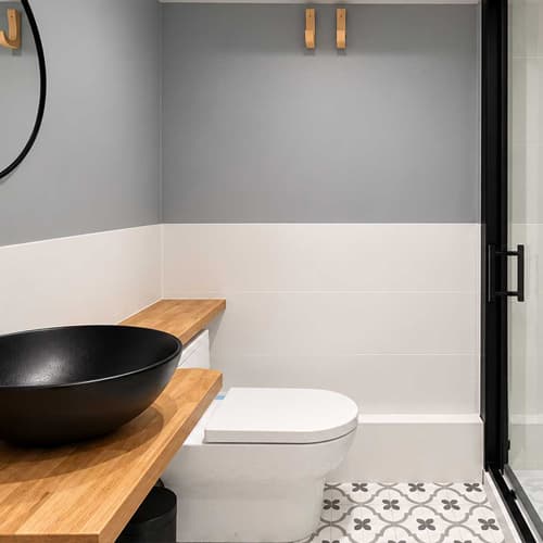 Baño reformado con mampara, lavabo sobre encimera de madera y suelo hidráulico en Ferrol