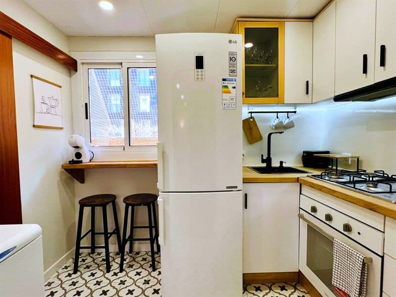 Cocina reformada con frigorífico integrado, barra de desayuno y suelo hidráulico en Ferrol