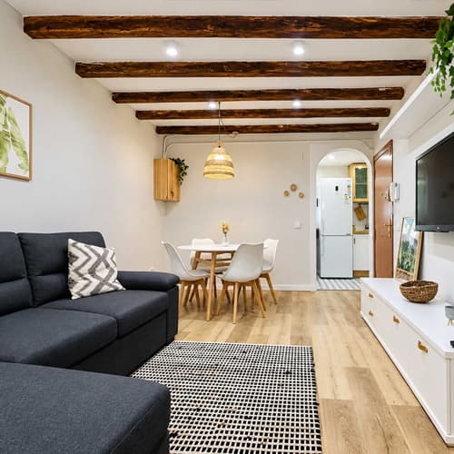 Salón reformado por Galihogar con vigas de madera vistas y suelo laminado en Ferrol
