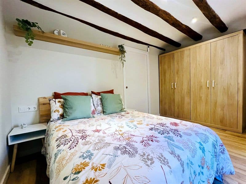Dormitorio con vigas de madera y armario empotrado reformado por Galihogar en Ferrol