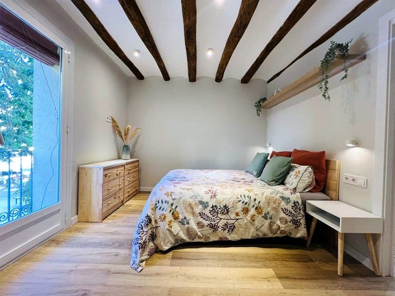 Dormitorio con paredes recién pintadas en blanco y vigas vistas en Ferrol